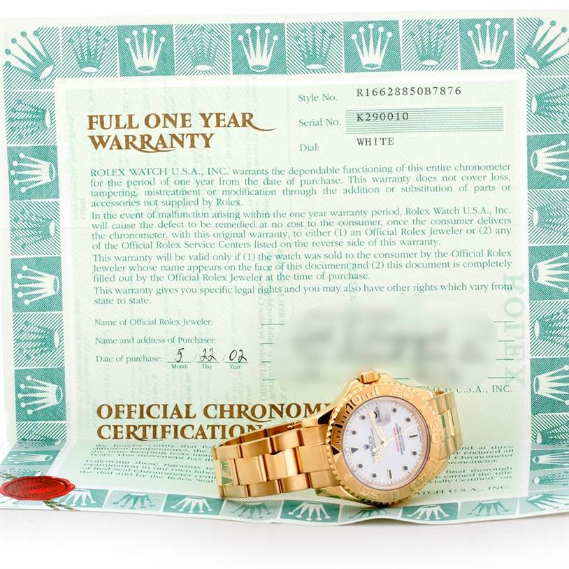 The image shows a Rolex Yacht-Master 16628 Men's Yellow Gold White Dial 16628 Men's Yellow Gold White Dial watch placed on top of an official warranty and certification document.