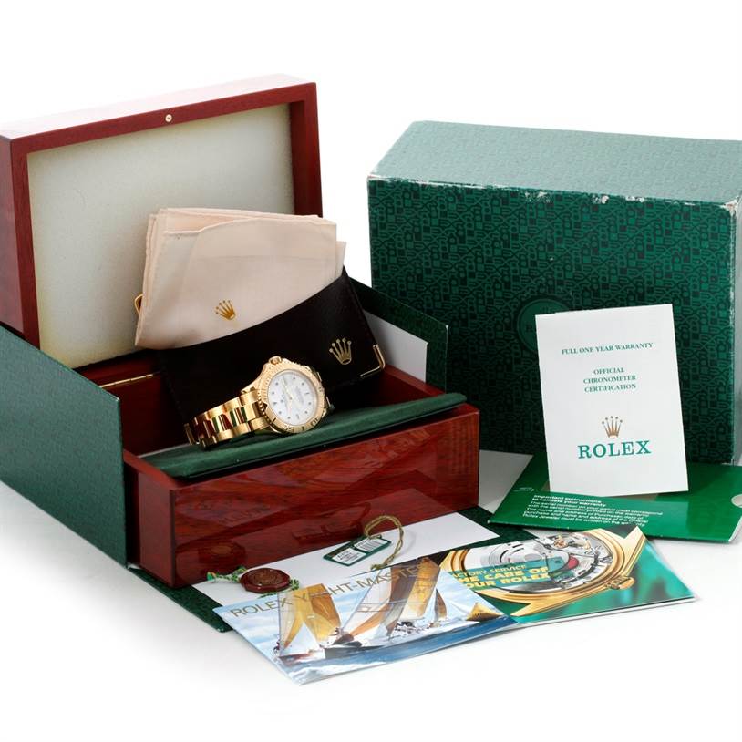 The image shows a Rolex Yacht-Master 16628 Men's Yellow Gold White Dial 16628 Men's Yellow Gold White Dial watch, its box, warranty card, cloth pouches, and manuals, viewed from a front angle.