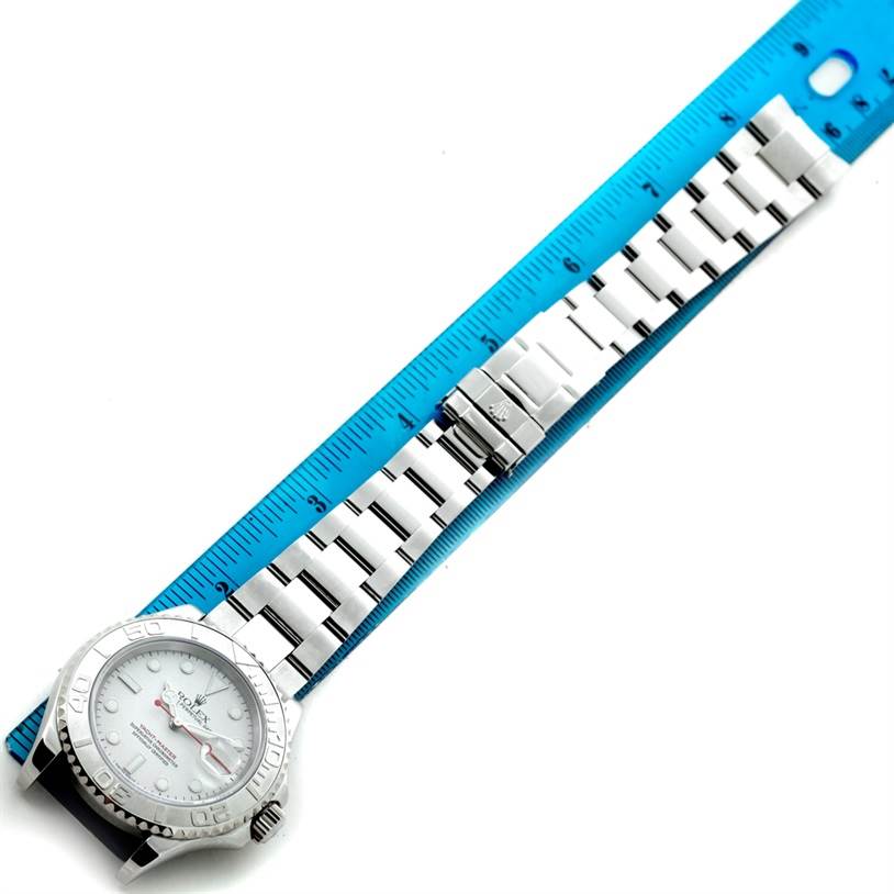 The Rolex Yacht-Master 16622 Men's Stainless Steel Silver Dial 16622 Men's Stainless Steel Silver Dial watch is shown flat with a metal bracelet next to a blue ruler for measurement.