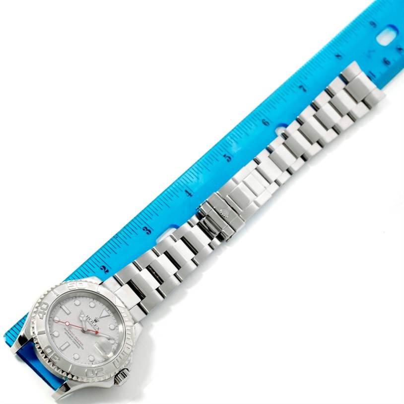 The Rolex Yacht-Master 16622 Men's Stainless Steel Silver Dial 16622 Men's Stainless Steel Silver Dial watch is shown lying flat against a blue ruler, displaying its face, bezel, and full metal bracelet.