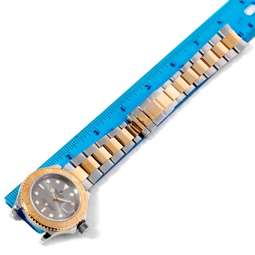 The image shows a Rolex Yacht-Master 16623 Men's Stainless Steel Grey Dial 16623 Men's Stainless Steel Grey Dial watch at an overhead angle alongside a blue ruler, displaying the face and the two-tone metal bracelet.
