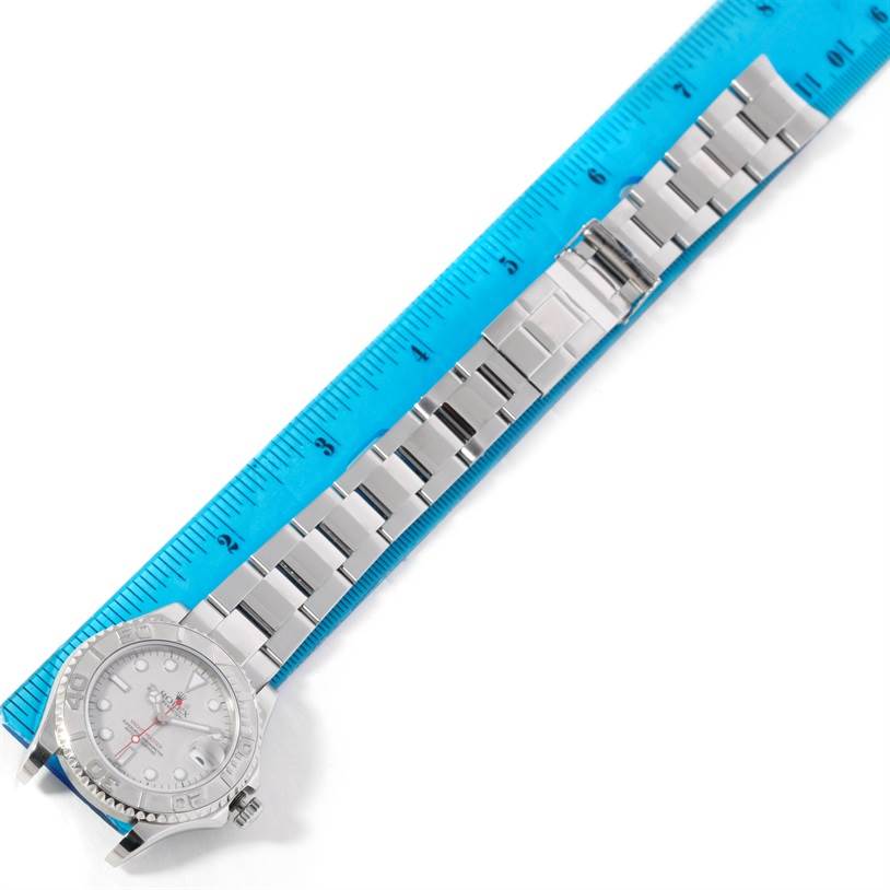 The image shows a top-down view of the Rolex Yacht-Master 168622 Stainless Steel Silver Dial 168622 Stainless Steel Silver Dial watch and its metal bracelet beside a blue ruler.