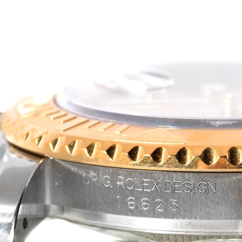 The image shows a close-up side view of a Rolex Yacht-Master 16623 Men's Stainless Steel Champagne Dial 16623 Men's Stainless Steel Champagne Dial watch, highlighting the gold bezel and engraved watch case.