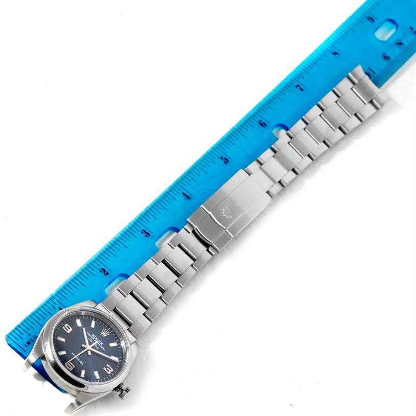 The image shows a Rolex Air-King 114200 Men's Stainless Steel Blue Dial 114200 Men's Stainless Steel Blue Dial watch laid flat with a blue ruler measuring its length, displaying the watch face and bracelet.