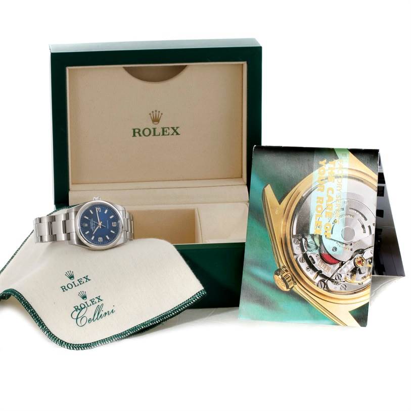 This image shows a Rolex Air-King 114200 Men's Stainless Steel Blue Dial 114200 Men's Stainless Steel Blue Dial watch, its box, a polishing cloth, and a booklet about the watch's care.
