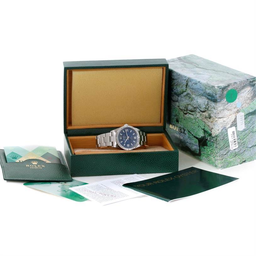 The Rolex Air-King 14010 Men's Stainless Steel Blue Dial 14010 Men's Stainless Steel Blue Dial watch is shown from the front inside its open box, along with manuals and outer packaging visible.