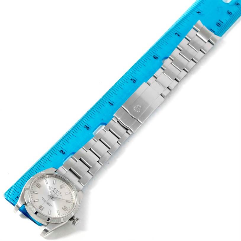 The image shows the Rolex Air-King 114210 Men's Stainless Steel Silver Dial 114210 Men's Stainless Steel Silver Dial watch laid flat next to a ruler, displaying the face, bracelet, and clasp.