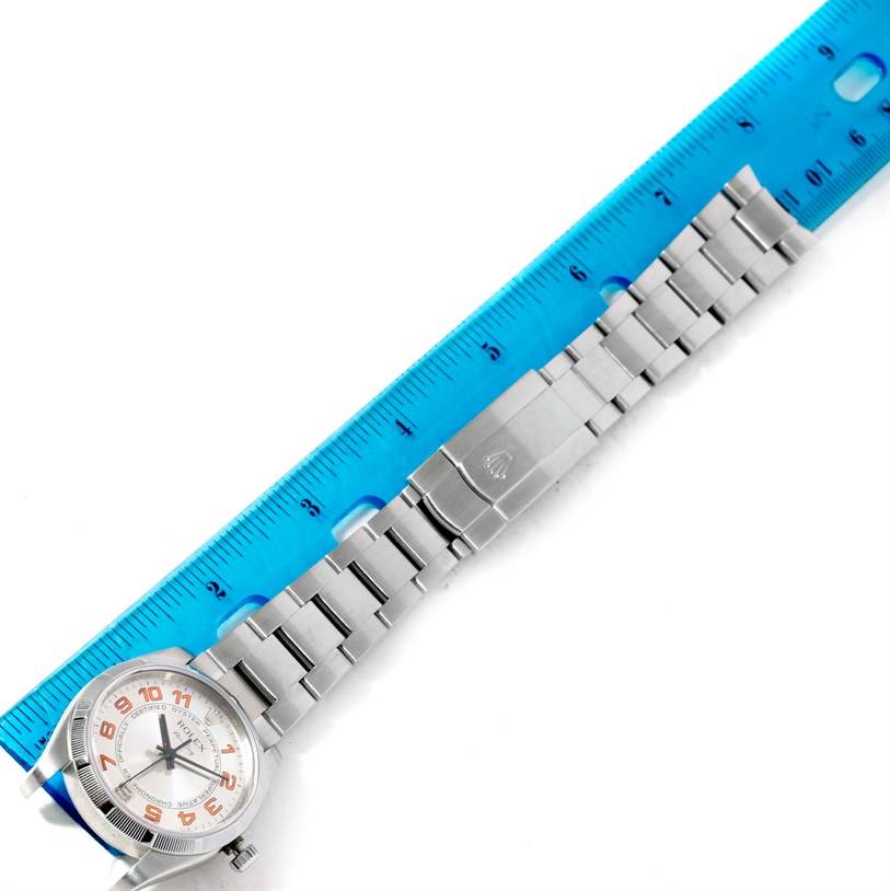 The image shows a Rolex Air-King 114210 Men's Stainless Steel Silver Dial 114210 Men's Stainless Steel Silver Dial watch laid flat with its face and metal bracelet visible, alongside a blue ruler for size reference.