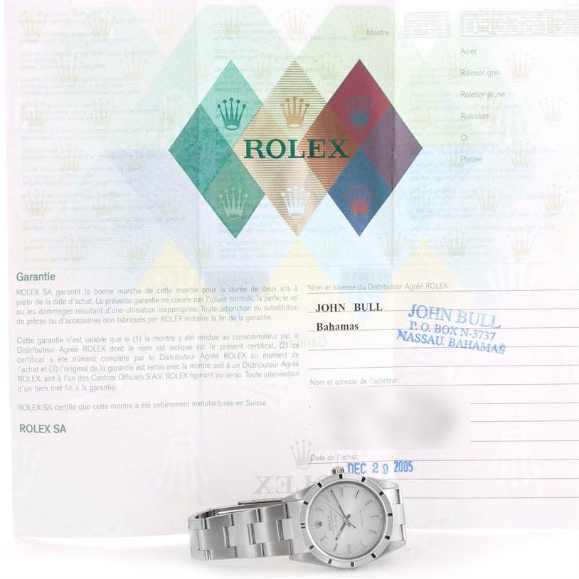 The image shows a Rolex Air-King 14010 Men's Stainless Steel Silver Dial 14010 Men's Stainless Steel Silver Dial watch resting on its side, accompanied by its warranty papers.