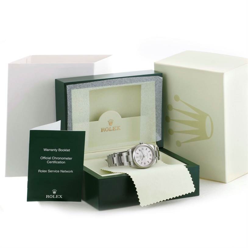 The Rolex Air-King 114200 Men's Stainless Steel Silver Dial 114200 Men's Stainless Steel Silver Dial watch is displayed in its case along with a warranty booklet and protective cloth, photographed from a front angle.