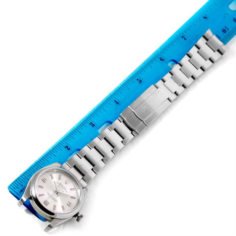 The Rolex Air-King 114200 Men's Stainless Steel Silver Dial 114200 Men's Stainless Steel Silver Dial watch is shown from a top-down angle, displaying the face, bracelet, and clasp alongside a blue ruler for scale.