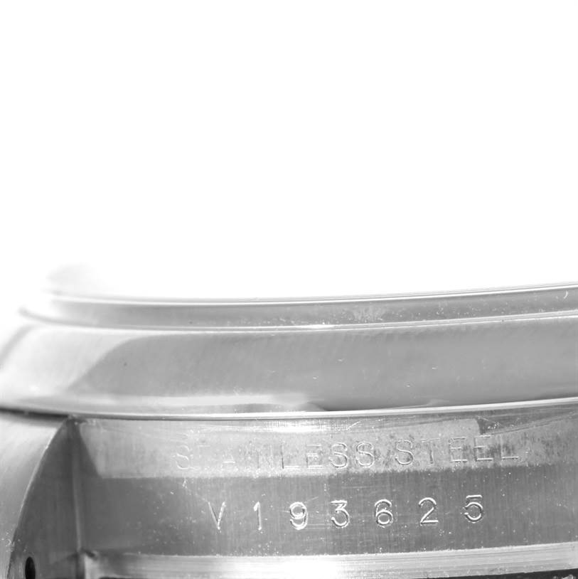 This close-up image shows part of the stainless steel edge and serial number of a Rolex Air-King 114200 Men's Stainless Steel Silver Dial 114200 Men's Stainless Steel Silver Dial watch.