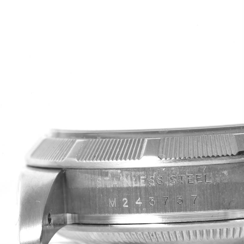 This image shows a close-up of the side of a stainless steel Rolex Air-King 114210 Men's Stainless Steel Blue Dial 114210 Men's Stainless Steel Blue Dial watch case, including part of the bezel and serial number.