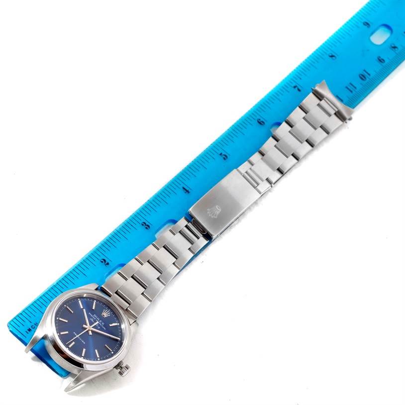 The Rolex Air-King 14000 Men's Stainless Steel Blue Dial 14000 Men's Stainless Steel Blue Dial watch is shown from an oblique angle, displaying its face, band, and clasp next to a ruler for scale.