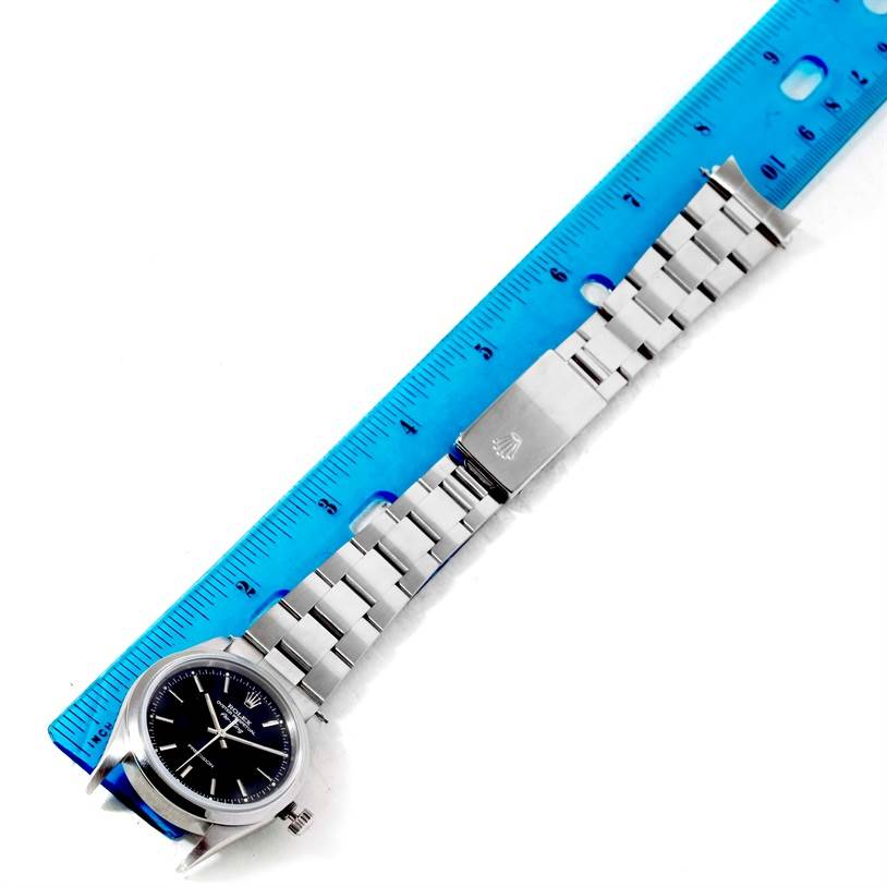 The Rolex Air-King 14000 Men's Stainless Steel Black Dial 14000 Men's Stainless Steel Black Dial watch is shown from a top-down angle, displaying the face, bracelet, and clasp beside a blue ruler for scale.