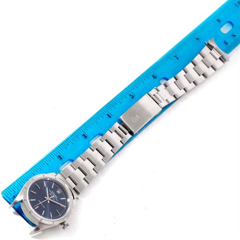 The Rolex Air-King 14010 Men's Stainless Steel Blue Dial 14010 Men's Stainless Steel Blue Dial watch is shown flat with its face, bracelet, and clasp fully visible next to a blue ruler.