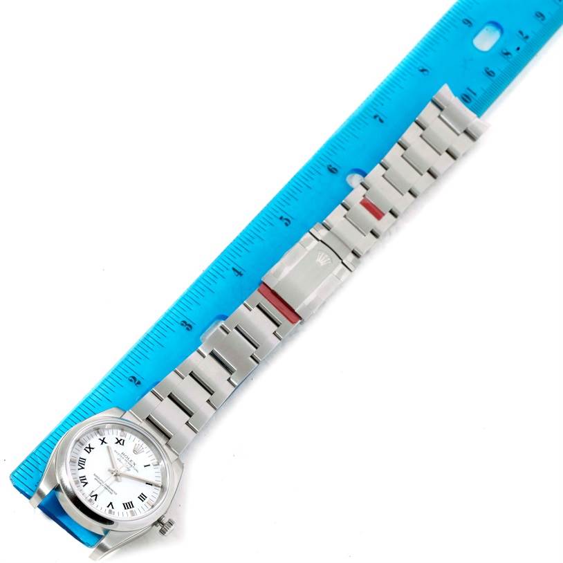 The Rolex Air-King 114200 Men's Stainless Steel White Dial 114200 Men's Stainless Steel White Dial watch is shown from a top view, displaying the face, bracelet, and clasp alongside a ruler for scale.