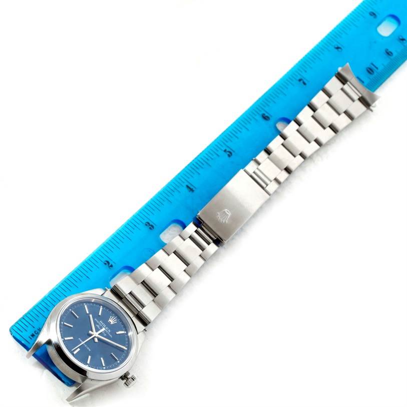 This image shows a Rolex Air-King 14000 Men's Stainless Steel Blue Dial 14000 Men's Stainless Steel Blue Dial watch laid flat next to a blue ruler, highlighting its link bracelet and blue dial.