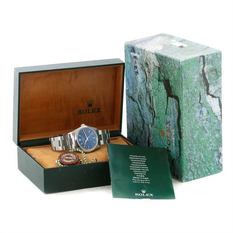 The image shows a Rolex Air-King 14000 Men's Stainless Steel Blue Dial 14000 Men's Stainless Steel Blue Dial watch with a blue dial, its original box, warranty card, and green instruction booklet.