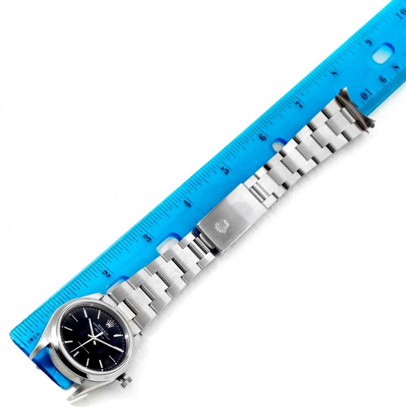 The Rolex Air-King 14000 Men's Stainless Steel Black Dial 14000 Men's Stainless Steel Black Dial watch is shown from an overhead angle, displaying the face, bracelet, and clasp alongside a blue ruler.