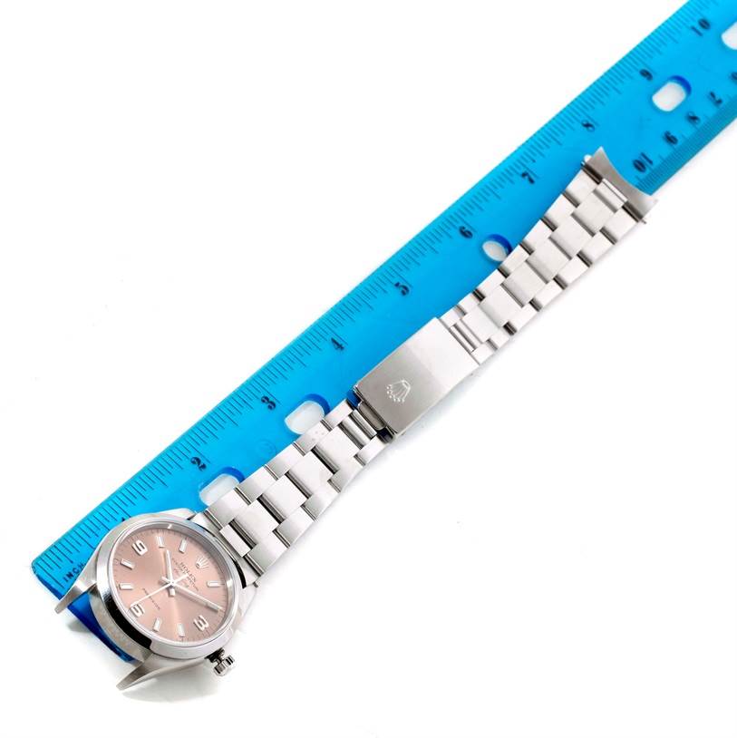 This image shows the Rolex Air-King 14000 Men's Stainless Steel Pink Dial 14000 Men's Stainless Steel Pink Dial watch laid parallel to a blue ruler, displaying the face, bracelet, and clasp.