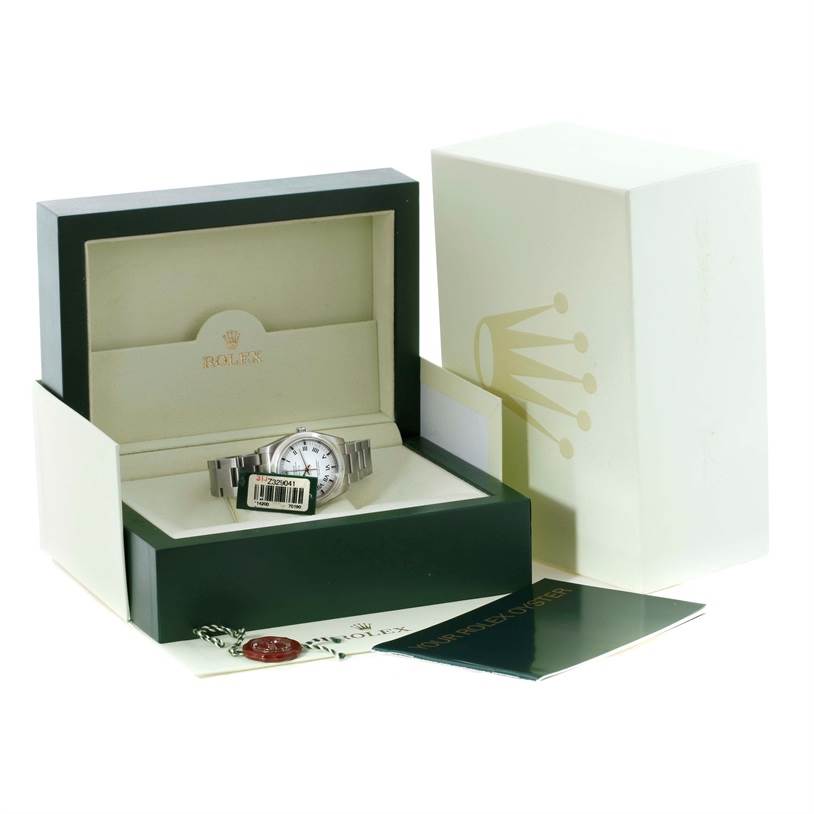 The Rolex Air-King 114200 Men's Stainless Steel White Dial 114200 Men's Stainless Steel White Dial is shown in its open display box with tags and papers, along with the outer box in the background.