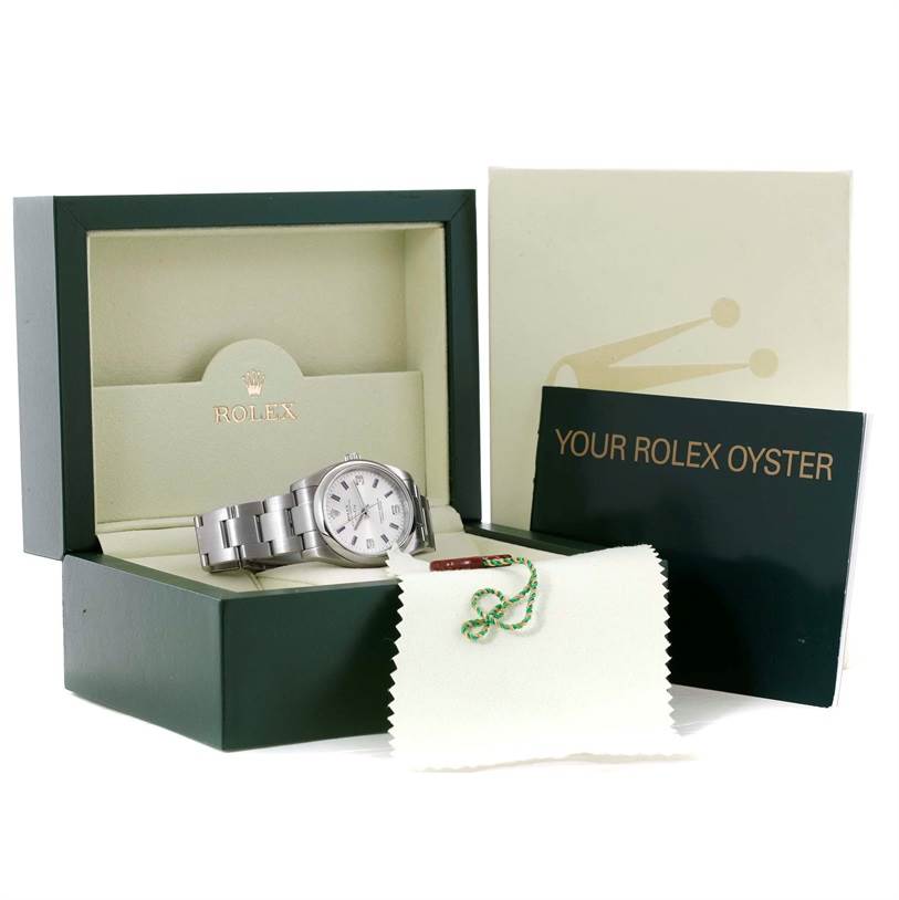The Rolex Air-King 114200 Men's Stainless Steel Silver Dial 114200 Men's Stainless Steel Silver Dial watch is angled in its open box with extra accessories including a booklet and a cleaning cloth.