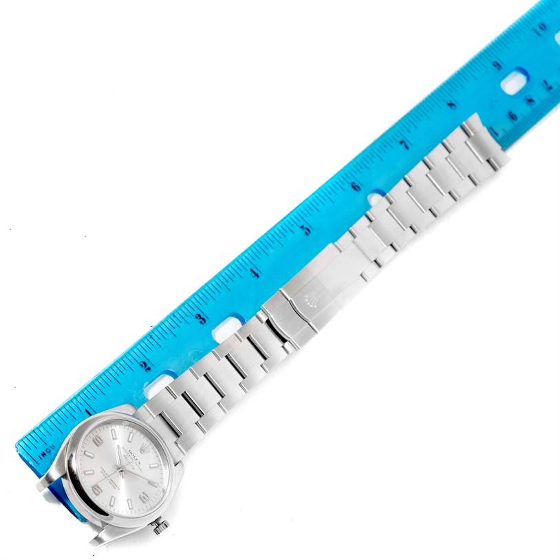 The image shows a Rolex Air-King 114200SASO Men's Stainless Steel Silver Dial 114200SASO Men's Stainless Steel Silver Dial watch laid flat next to a blue ruler, displaying the face, bracelet, and clasp.