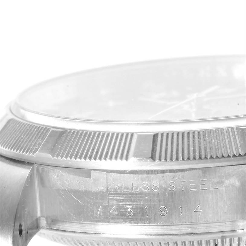 The image shows a close-up of the bezel and case, with "STAINLESS STEEL" and serial numbers engraved, of a Rolex Air-King 114200BLRO Men's Stainless Steel Blue Dial 114200BLRO Men's Stainless Steel Blue Dial watch.