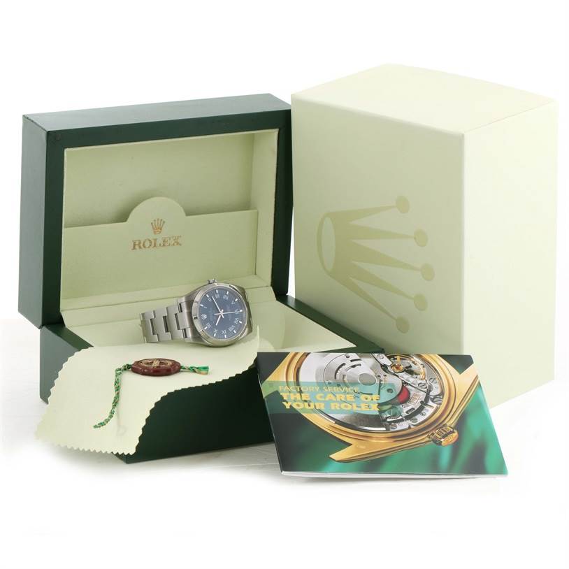 The image shows a Rolex Air-King 114200BLRO Men's Stainless Steel Blue Dial 114200BLRO Men's Stainless Steel Blue Dial watch at a slight angle, in its opened box with a booklet and accessories.