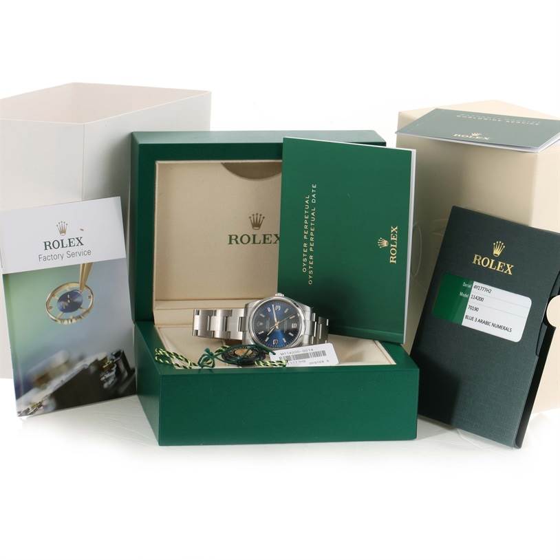 The image shows a Rolex Air-King 114200BLASO Men's Stainless Steel Blue Dial 114200BLASO Men's Stainless Steel Blue Dial watch with its green box, manuals, and factory service booklet.