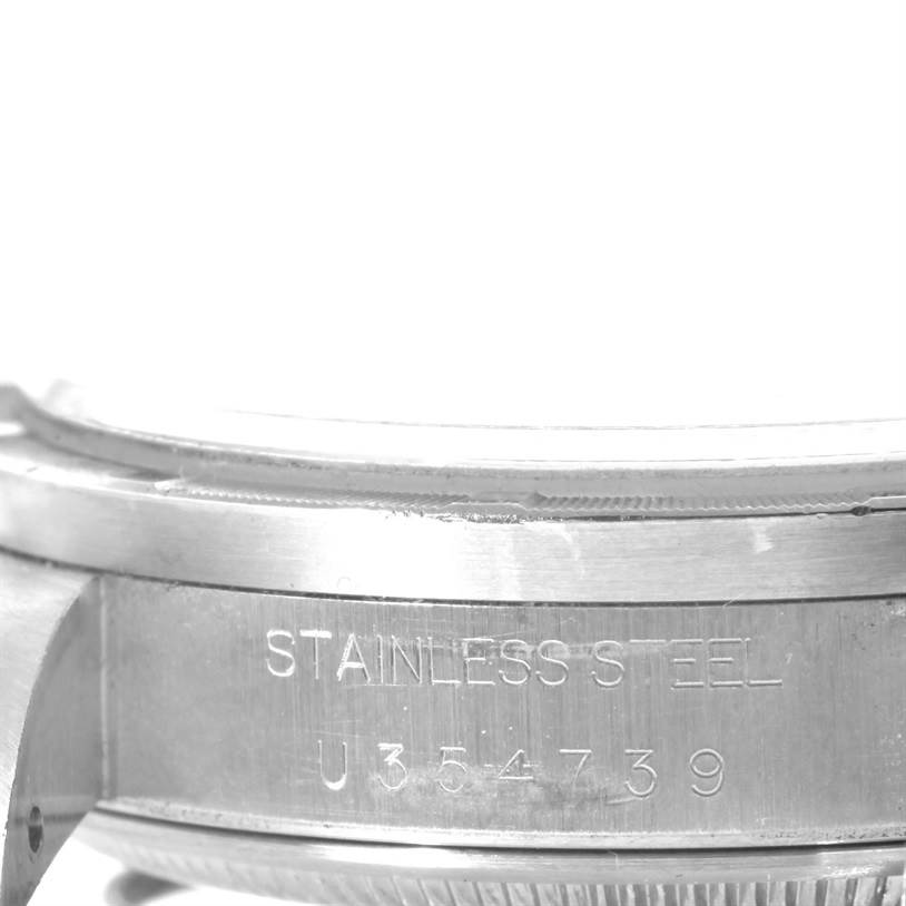 This image shows a close-up of the side of a Rolex Air-King 14010 Men's Stainless Steel Silver Dial 14010 Men's Stainless Steel Silver Dial watch case, focusing on the engraved serial number and the stainless steel label.