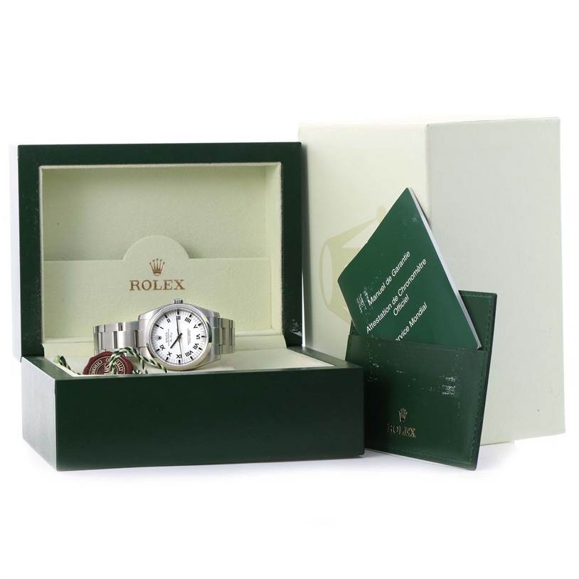 The Rolex Air-King 114200 Stainless Steel White Dial 114200 Stainless Steel White Dial watch is shown front-facing in its open box, with accompanying tags and manuals to the side.