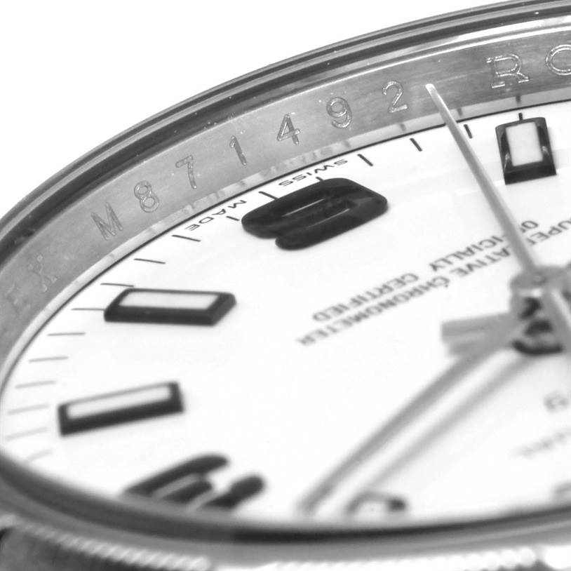 The close-up image of the Rolex Air-King 114210 Men's Stainless Steel White Dial 114210 Men's Stainless Steel White Dial watch shows part of the dial, bezel, and a portion of the watch's hand.