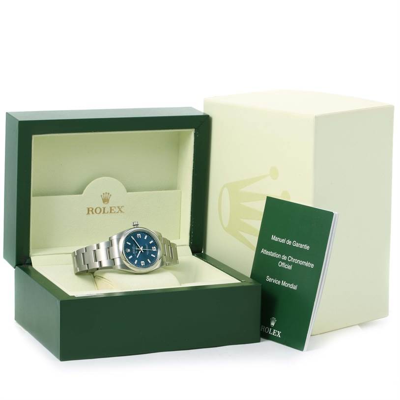The Rolex Air-King 114200BLASO Men's Stainless Steel Blue Dial 114200BLASO Men's Stainless Steel Blue Dial watch is displayed in an open box, along with warranty and service manuals.