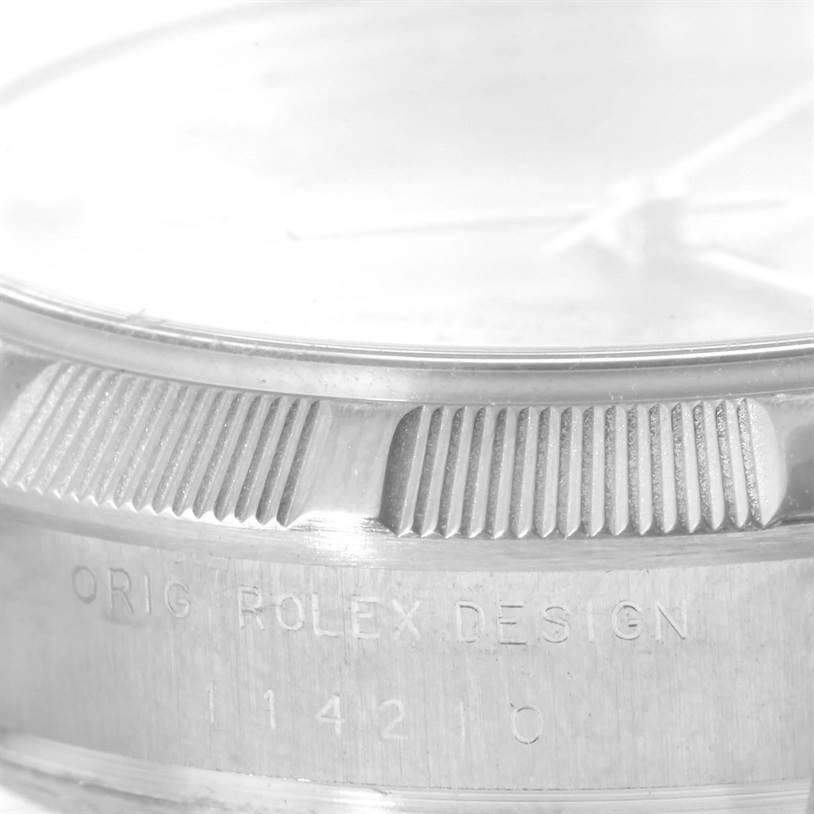 This close-up image of a Rolex Air-King 114210 Men's Stainless Steel Silver Dial 114210 Men's Stainless Steel Silver Dial watch focuses on the bezel and the text "ORIG ROLEX DESIGN" with model number 114210.