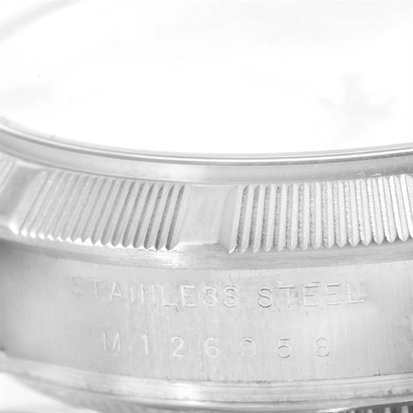 This close-up angle of the Rolex Air-King 114210 Men's Stainless Steel Silver Dial 114210 Men's Stainless Steel Silver Dial model shows part of the bezel and the "Stainless Steel" engraving.