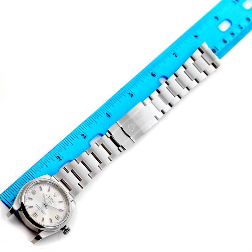 The image shows a Rolex Air-King 114200 Men's Stainless Steel Silver Dial 114200 Men's Stainless Steel Silver Dial watch with its bracelet and clasp, placed alongside a blue ruler.