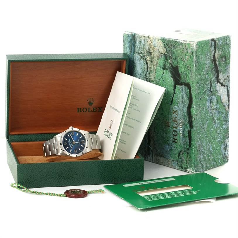 This image displays a Rolex Air-King 14010 Men's Stainless Steel Blue Dial 14010 Men's Stainless Steel Blue Dial watch at an angle in its open box with accompanying documents and packaging.