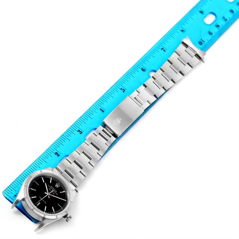 The image shows a top-down view of a Rolex Air-King 14010 Men's Stainless Steel Black Dial 14010 Men's Stainless Steel Black Dial watch with its bracelet laid out beside a blue ruler for scale.