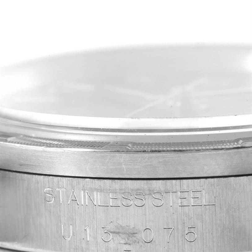 This image shows a close-up of the side of a Rolex Air-King 14010 Men's Stainless Steel Black Dial 14010 Men's Stainless Steel Black Dial watch, highlighting the "STAINLESS STEEL" engraving and part of the crystal.