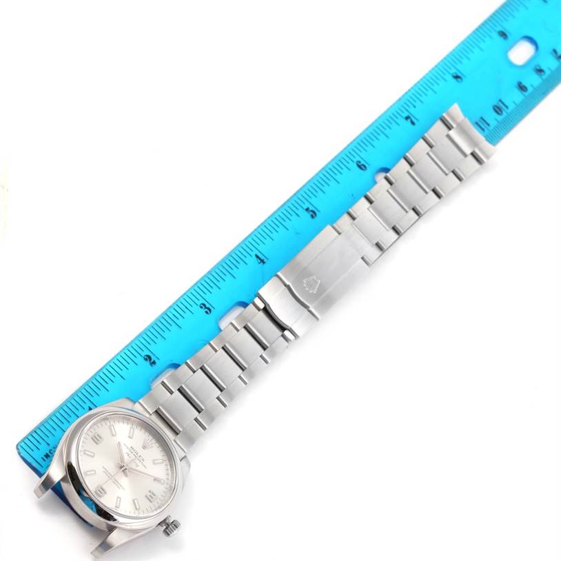 The image shows a Rolex Air-King 114200 Men's Stainless Steel Silver Dial 114200 Men's Stainless Steel Silver Dial watch laid flat with its band extended, next to a blue ruler for scale.