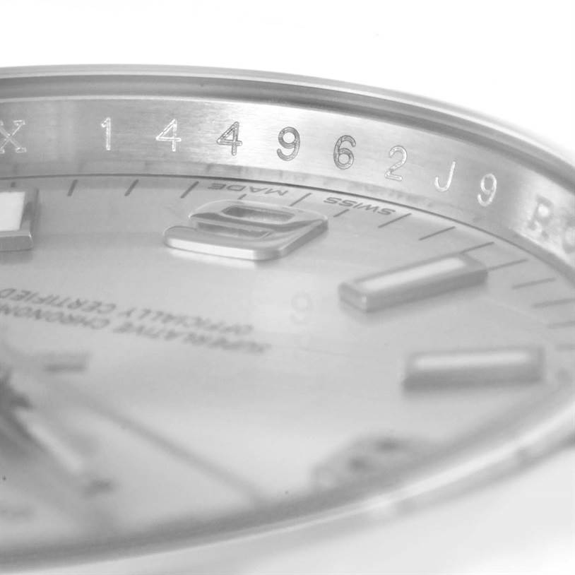 This close-up angled view of the Rolex Air-King 114200 Men's Stainless Steel Silver Dial 114200 Men's Stainless Steel Silver Dial model shows part of the dial and bezel with some numerical engravings.