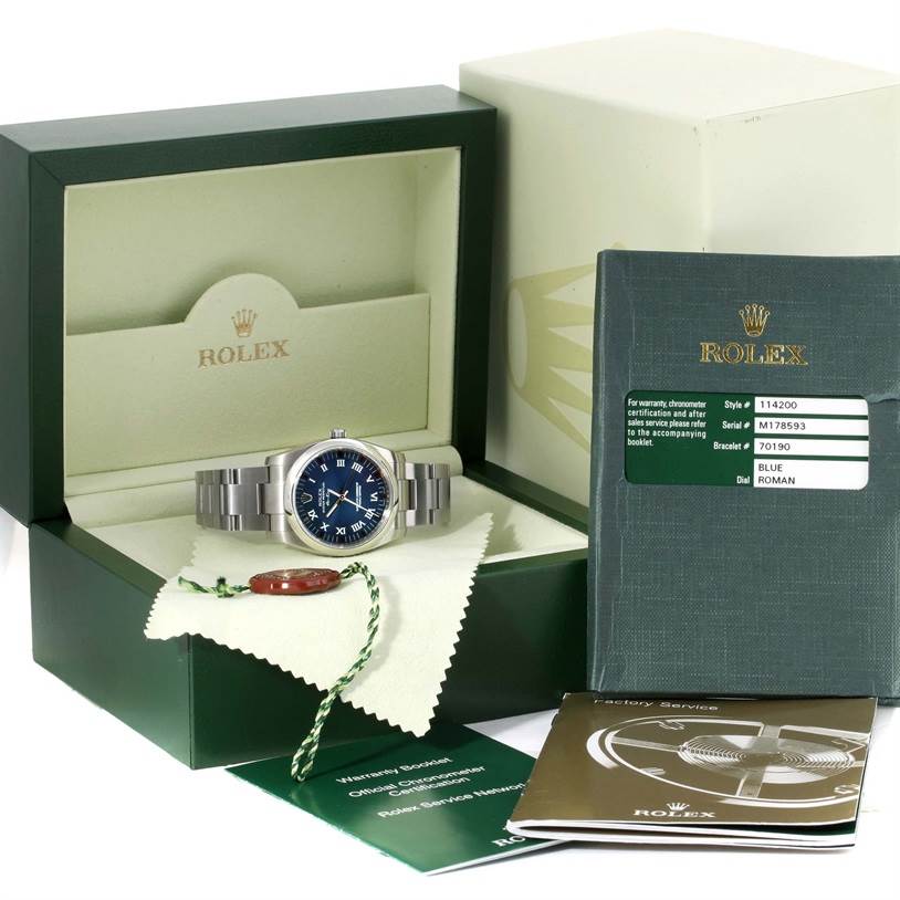 The image shows a Rolex Air-King 114200 Men's Stainless Steel Blue Dial 114200 Men's Stainless Steel Blue Dial watch in its box with a blue dial, accompanying documents, and tags.