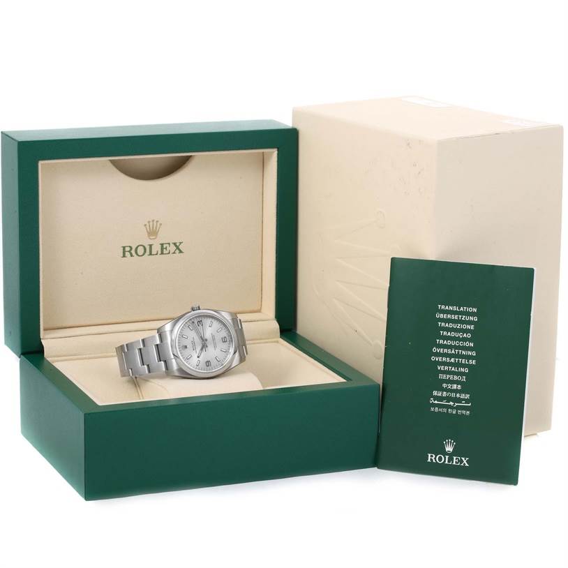 The Rolex Air-King 114200 Men's Stainless Steel Silver Dial 114200 Men's Stainless Steel Silver Dial watch is displayed in an open box, accompanied by its cover and a booklet.