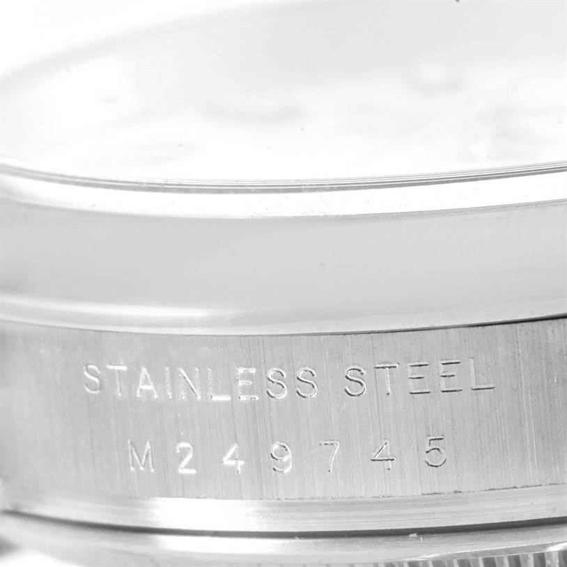 The image shows a close-up side view of a Rolex Air-King 114200 Men's Stainless Steel White Dial 114200 Men's Stainless Steel White Dial watch case, focusing on the stainless steel label and serial number.