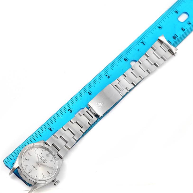 The Rolex Air-King 14010 Men's Stainless Steel Silver Dial 14010 Men's Stainless Steel Silver Dial watch is shown laid flat with a blue ruler measuring its length.