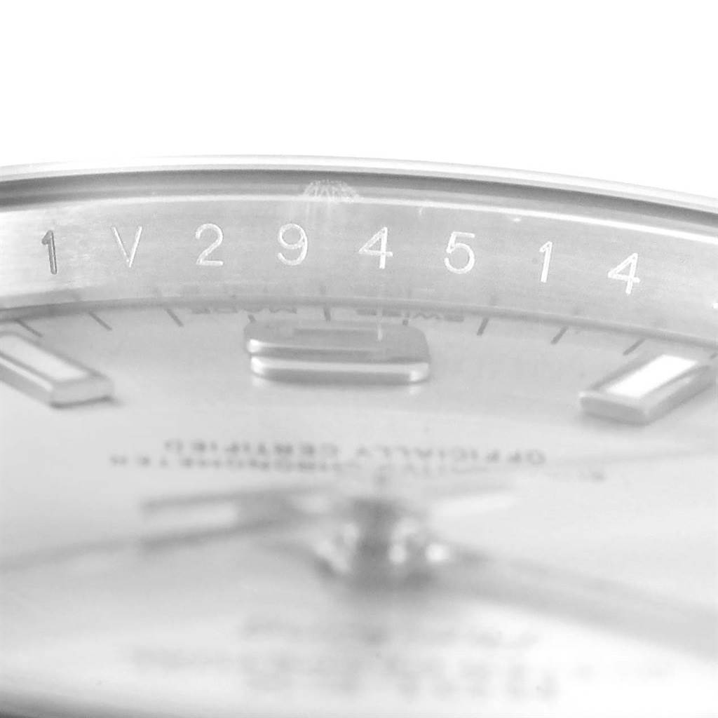 This close-up image of the Rolex Air-King 114200 Men's Stainless Steel Silver Dial 114200 Men's Stainless Steel Silver Dial watch shows a partial view of the dial and serial number on the inner bezel.