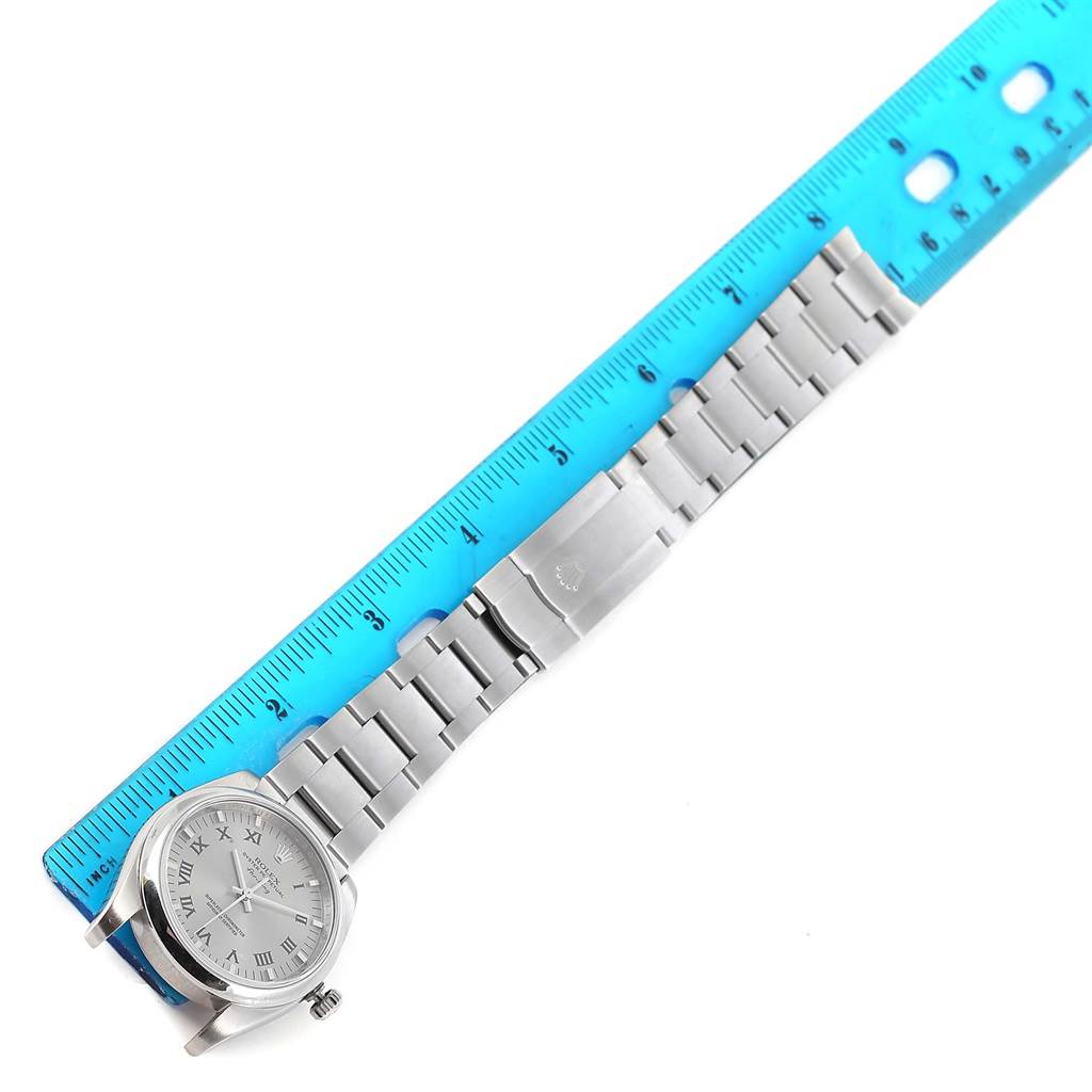 The image shows a Rolex Air-King 114200 Men's Stainless Steel Grey Dial 114200 Men's Stainless Steel Grey Dial watch with a stainless steel bracelet band and a blue ruler for scale, viewed from above.