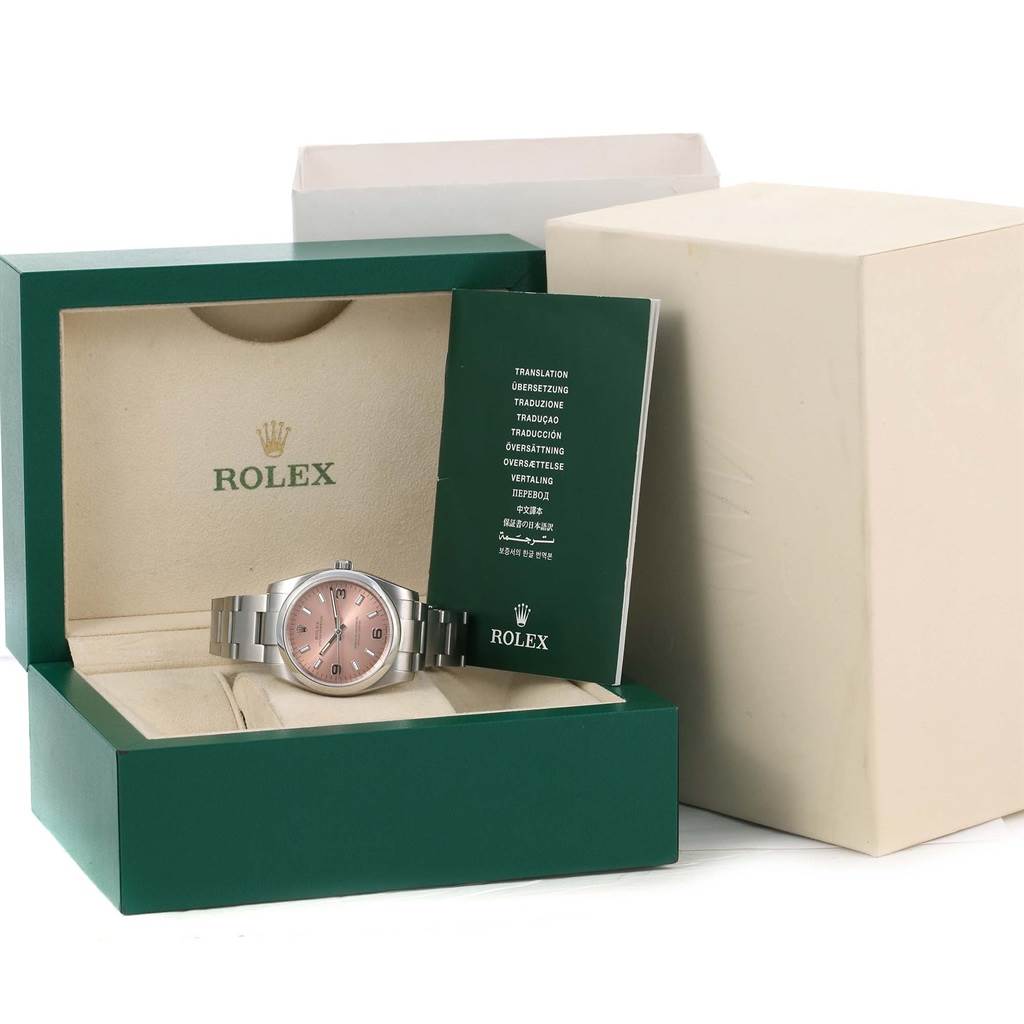 The Rolex Air-King 114200 Men's Stainless Steel Pink Dial 114200 Men's Stainless Steel Pink Dial watch is shown front-facing inside its green box, alongside its instruction booklet.